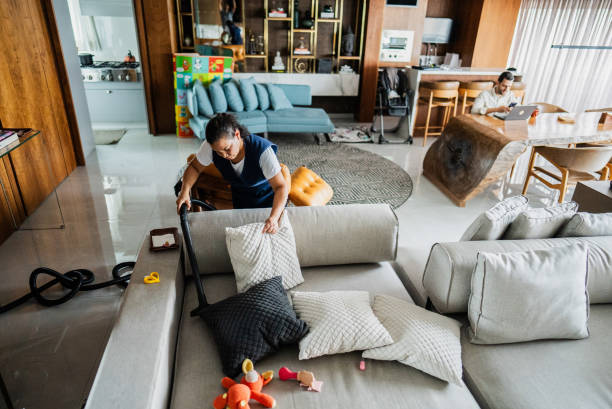 Cleaning housekeeper vacuuming sofa in a house
